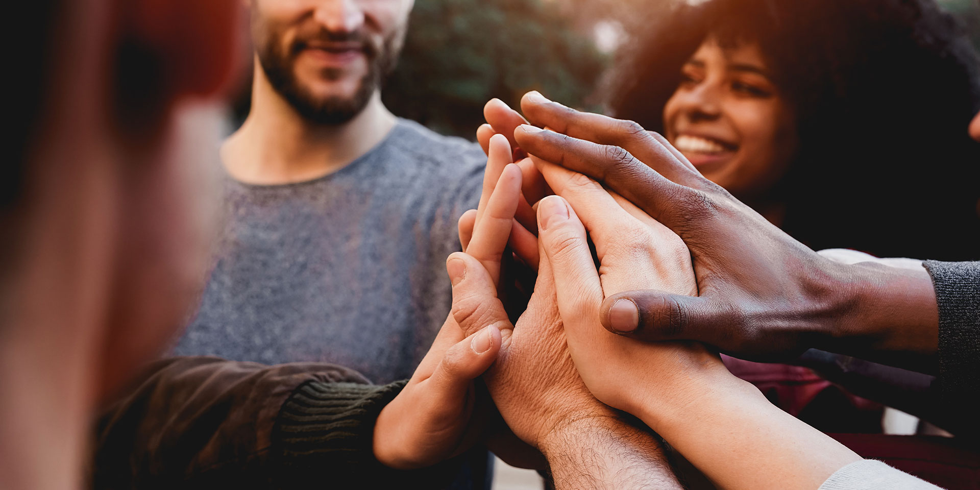 A group of diverse hands come together in a circle