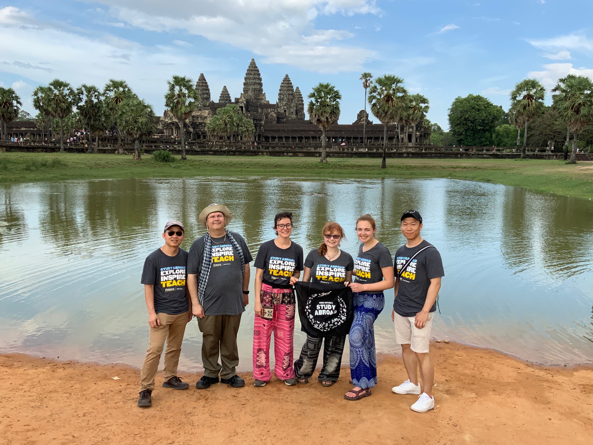 A group of study abroad participants standing in front of a large body of water. In the background is Cambodian architecture. 