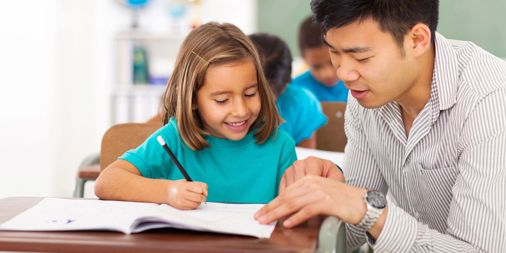A teacher works with a student at a desk