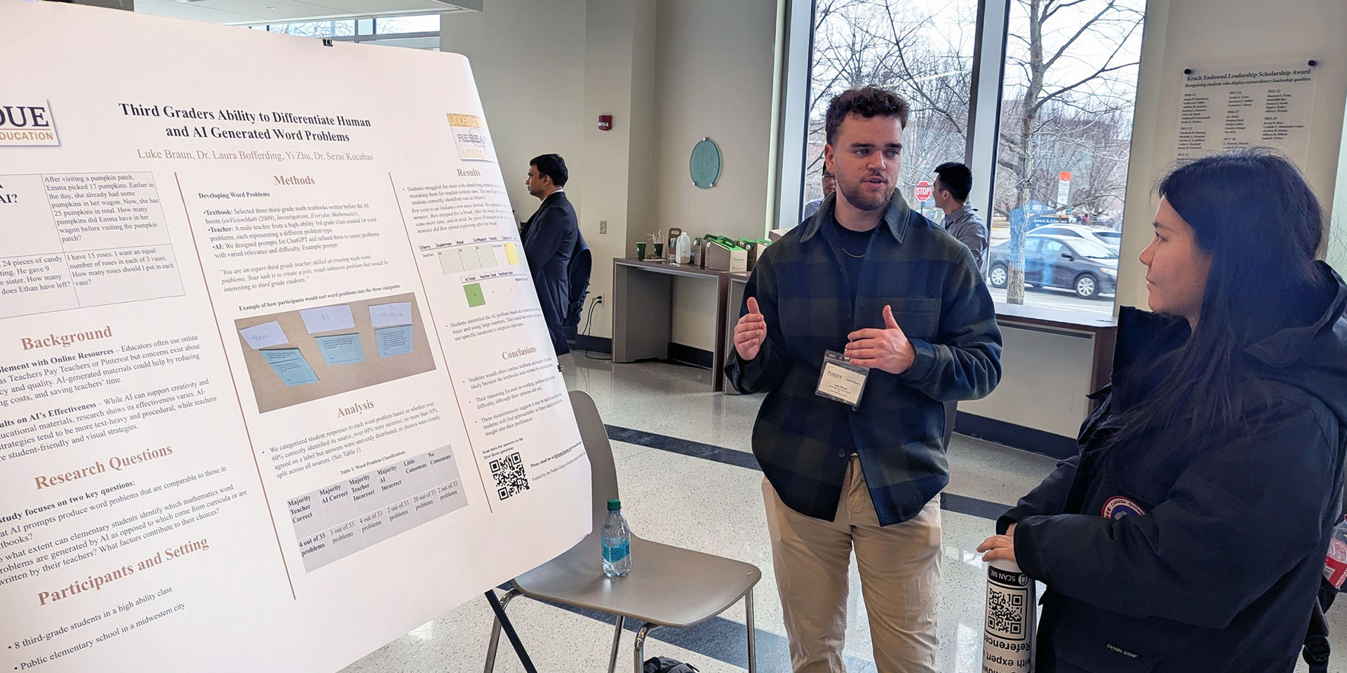 A student presents his research poster to a presentation attendee