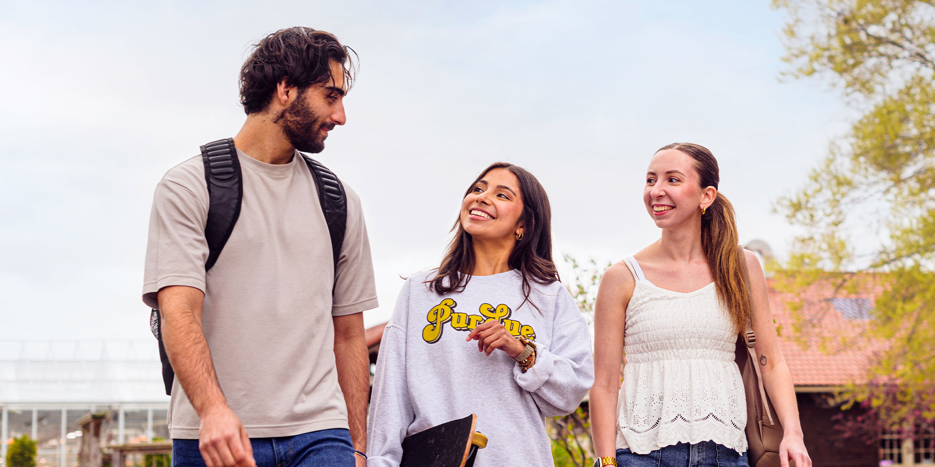 Three Purdue students walking outside. They are looking at each other and smiling. 