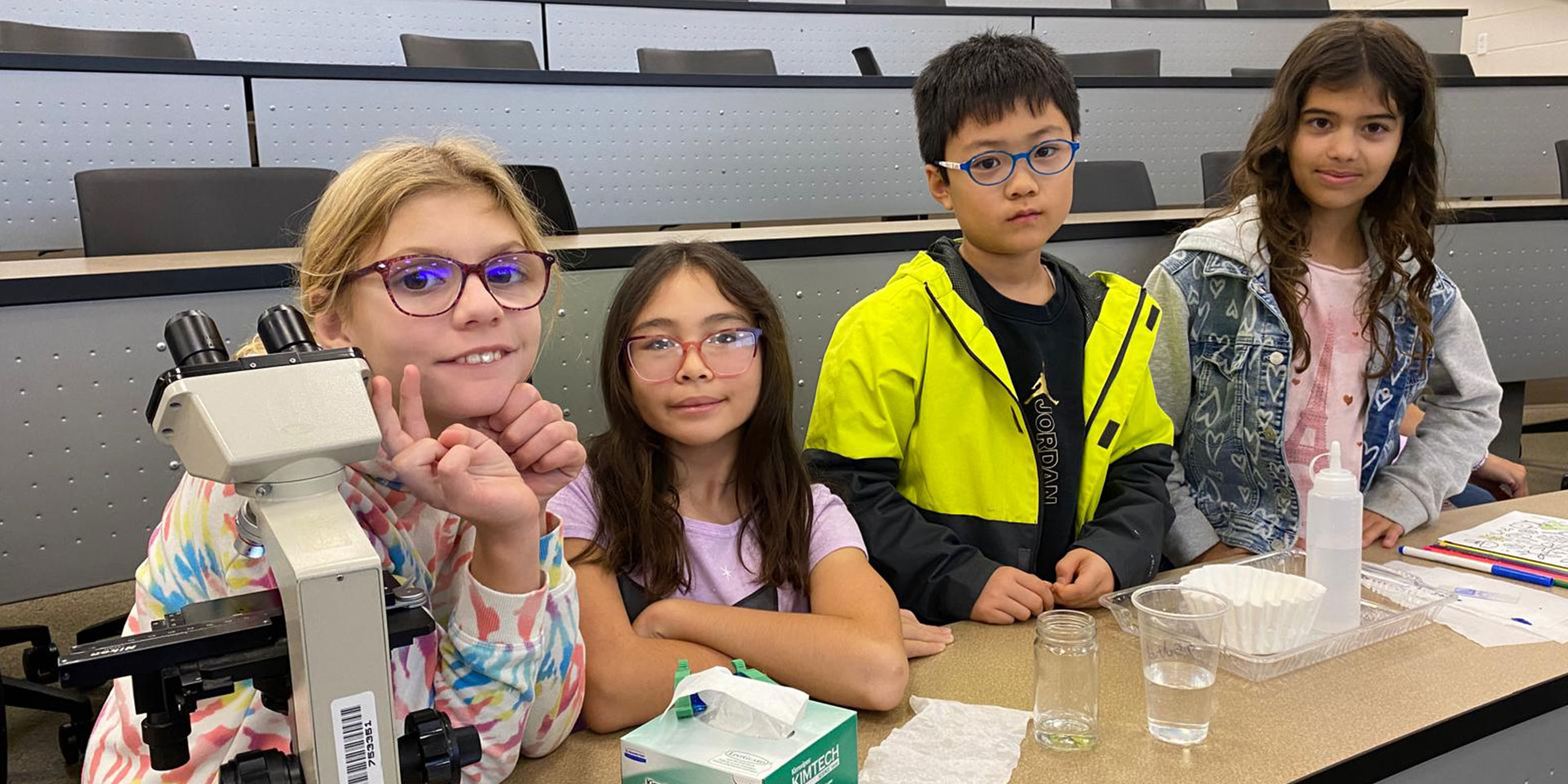 Super Saturday students work on a group project using a microscope