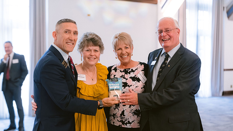 Phillip VanFossen, Theresa Eutsler, Bethany VanFossen, and Mark Eutsler holding a bag of Quinoa and smiling.