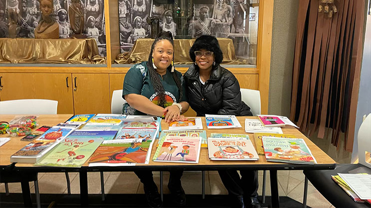 Two women seated at a table and smiling for a photo.