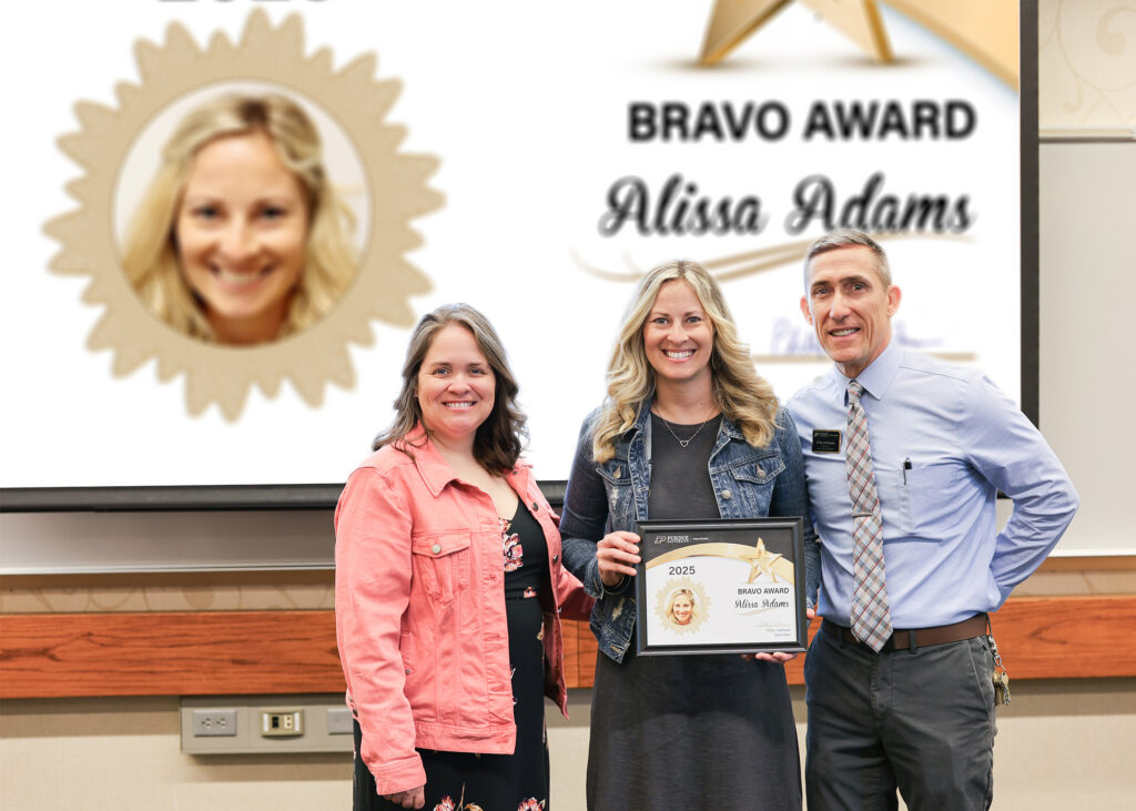 Alissa Adams holding a certificate. Standing with her are Jennifer Smith and Phillip VanFossen.