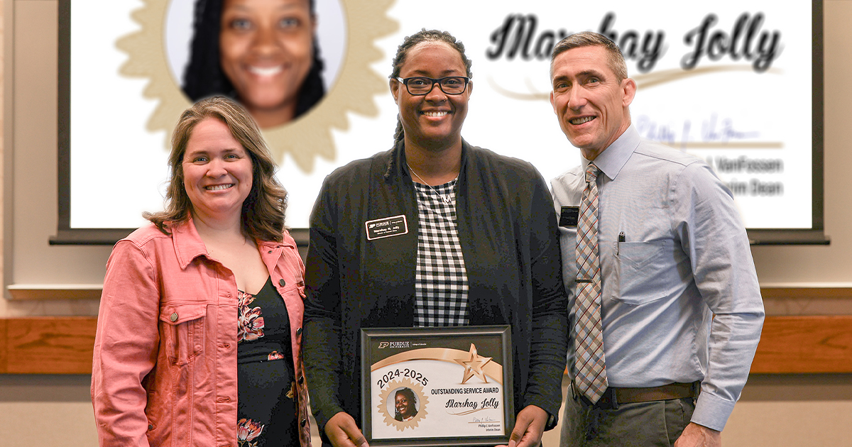 Marshay Jolly holding a certificate. Standing with her are Jennifer Smith and Phillip VanFossen.