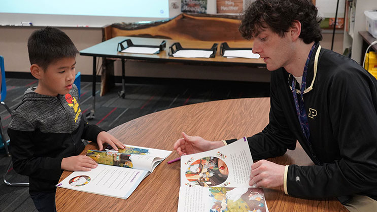 A Purdue University student teacher works with a student on their reading