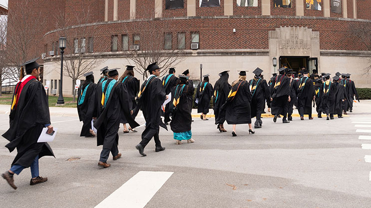 Purdue University students walk in their robes towards commencement