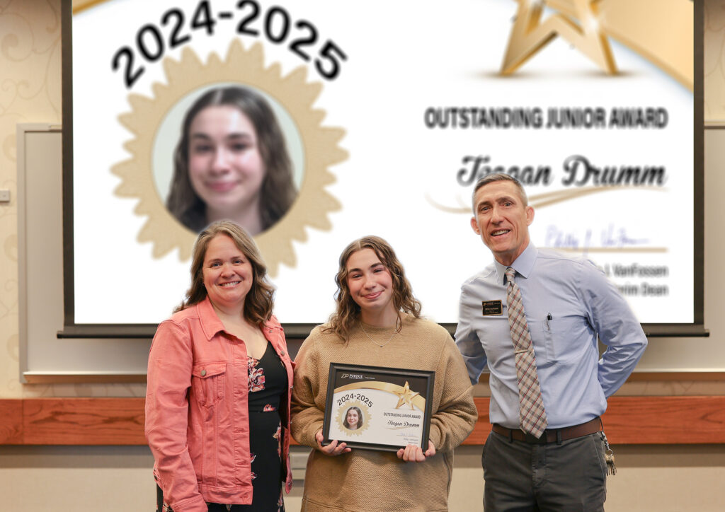 Teagan Drumm holding a certificate. Standing with her are Jennifer Smith and Phillip VanFossen.