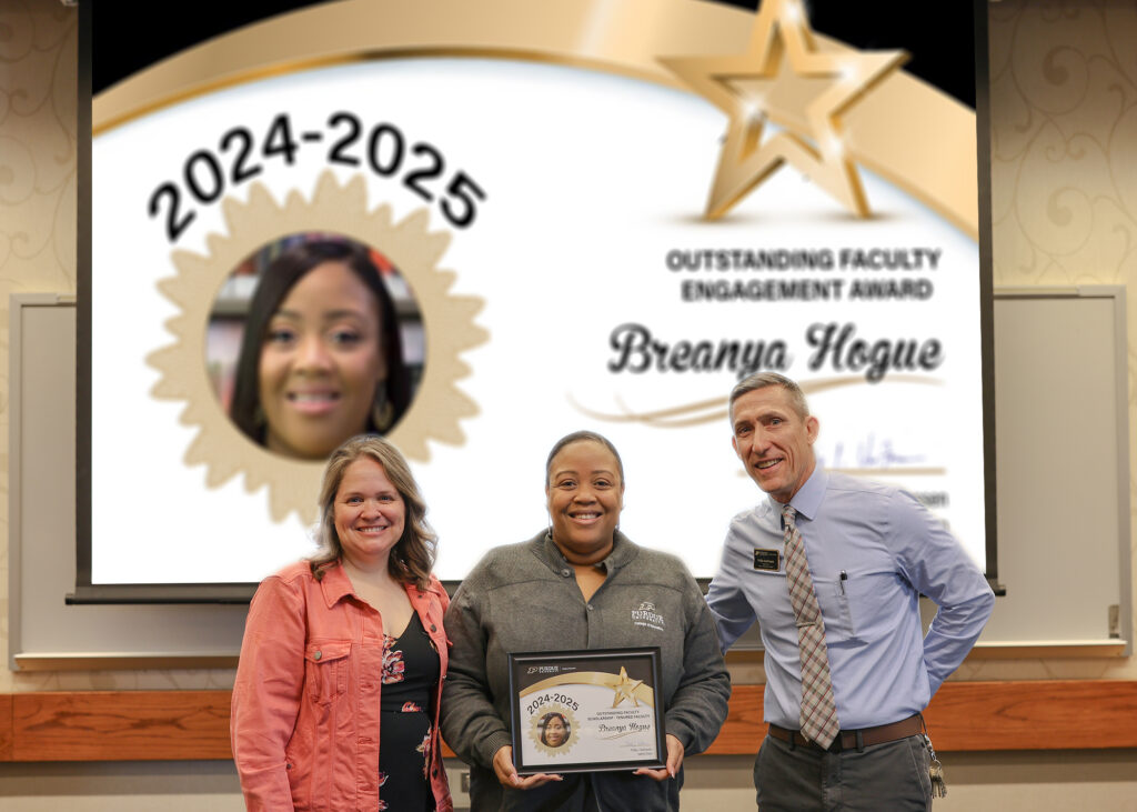 Dr. Breanya Hogue holding a certificate. Standing with her are Jennifer Smith and Phillip VanFossen.
