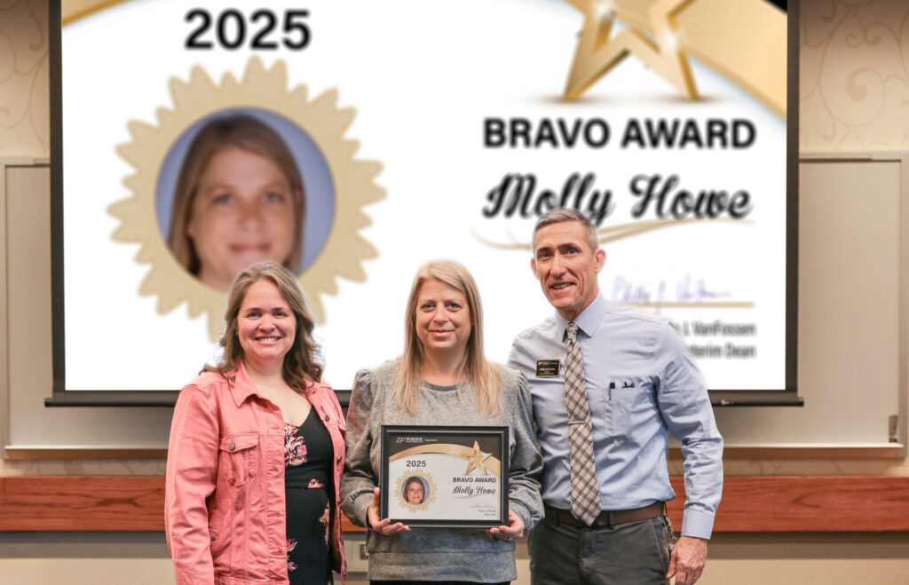 Molly Howe holding a certificate. Standing with her are Jennifer Smith and Phillip VanFossen.