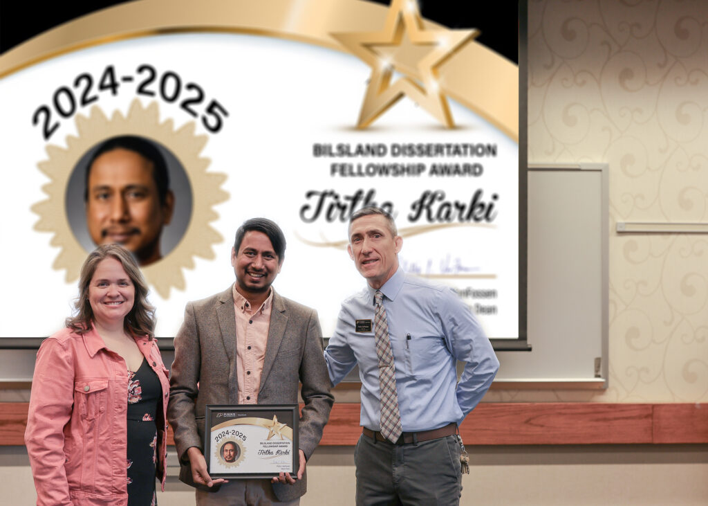 Tirtha Karki holding a certificate. Standing with him are Jennifer Smith and Phillip VanFossen.