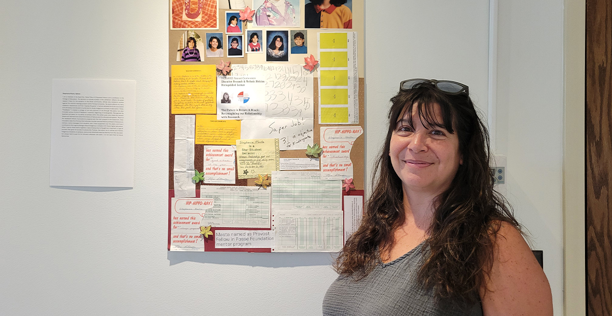 Stephanie Masta standing in front of a collage she created.