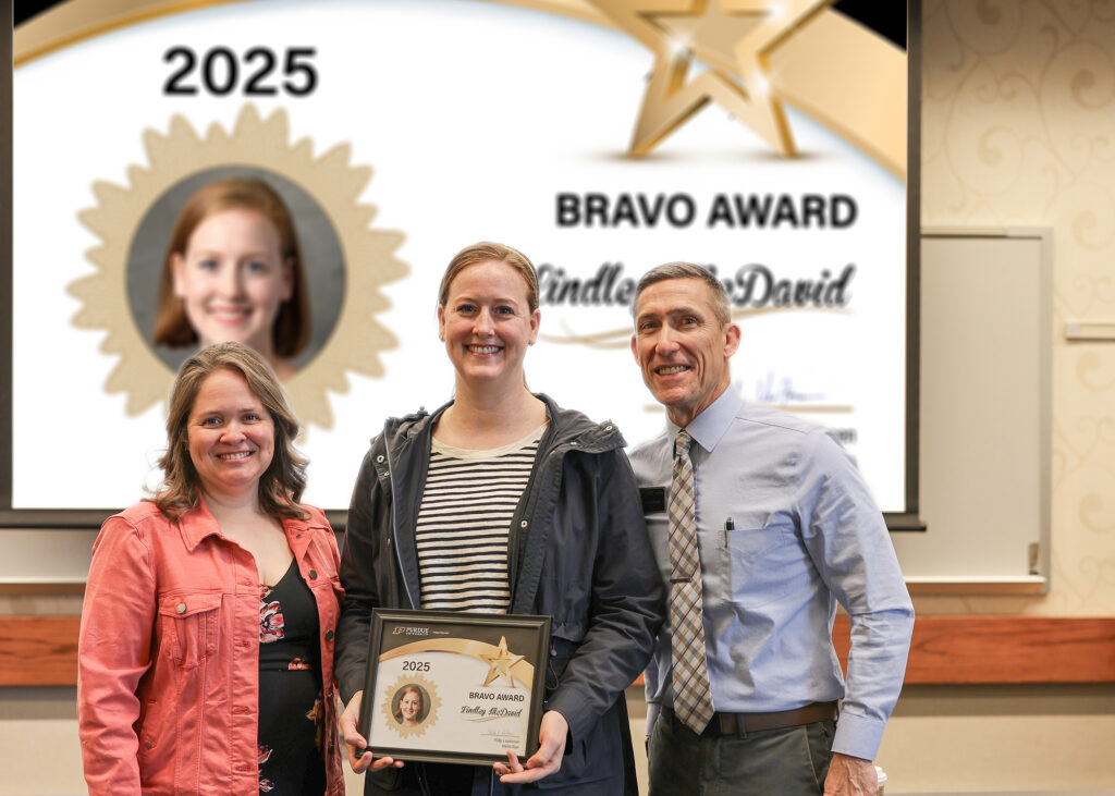 Dr. Lindley McDavid holding a certificate. Standing with her are Jennifer Smith and Phillip VanFossen.