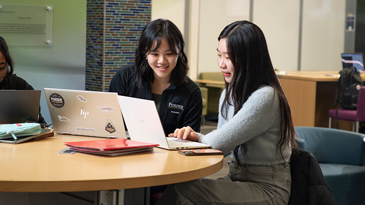 Two Purdue University students work on their laptops