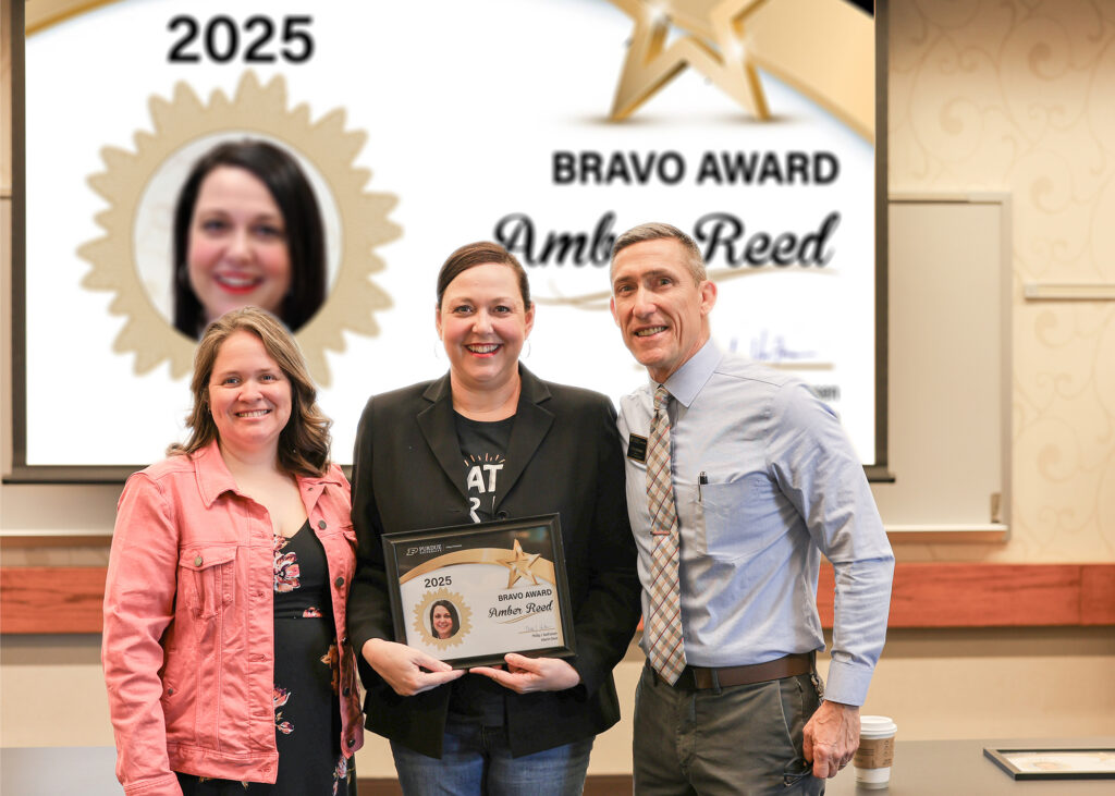 Dr. Amber Reed holding a certificate. Standing with her are Jennifer Smith and Phillip VanFossen.