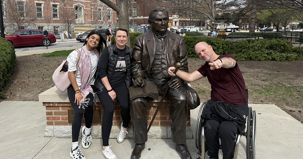 Vanessa Hernandez, Silva Laukkanen, and Dwayne Scheuneman seated next to a statue of John Purdue
