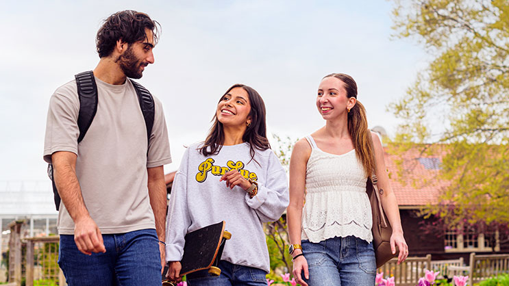 Three Purdue University students walk through campus in the spring