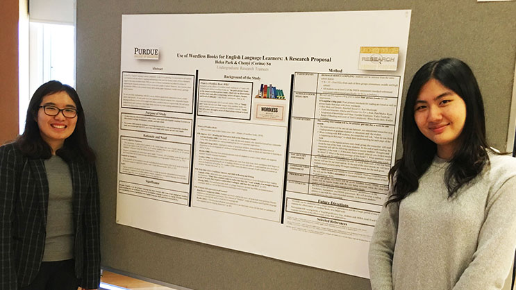 Two Purdue students in the URT Program stand in front of a research poster