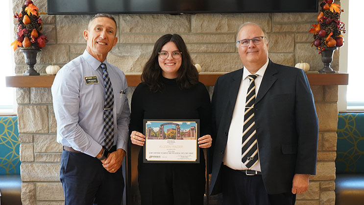 Allison Frazier holding a certificate. She is surrounded by Phil VanFossen and Wayne Wright.