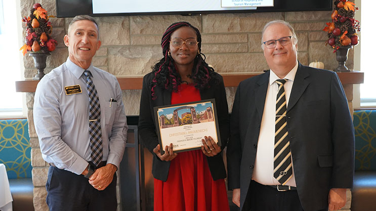 Christabel Anumenechi holding a certificate. She is surrounded by Phil VanFossen and Wayne Wright.
