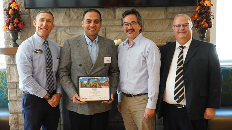 Farhad Roodi holding a certificate. He is surrounded by Phil VanFossen, Bill Watson, and Wayne Wright.