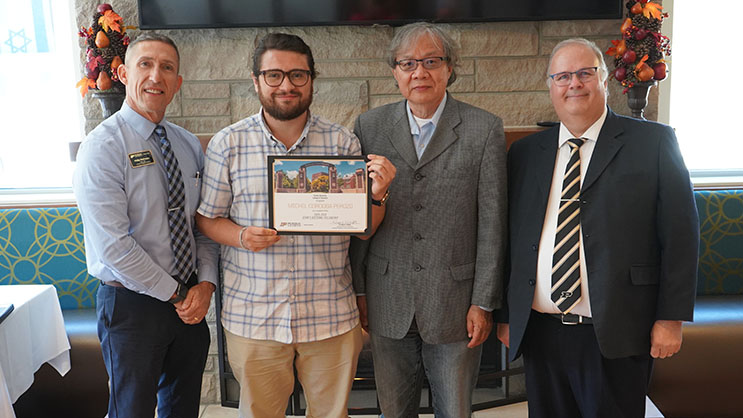 Michel Cordoba Perozo holding a certificate. He is surrounded by Phil VanFossen, Hua Hua Chang, and Wayne Wright.