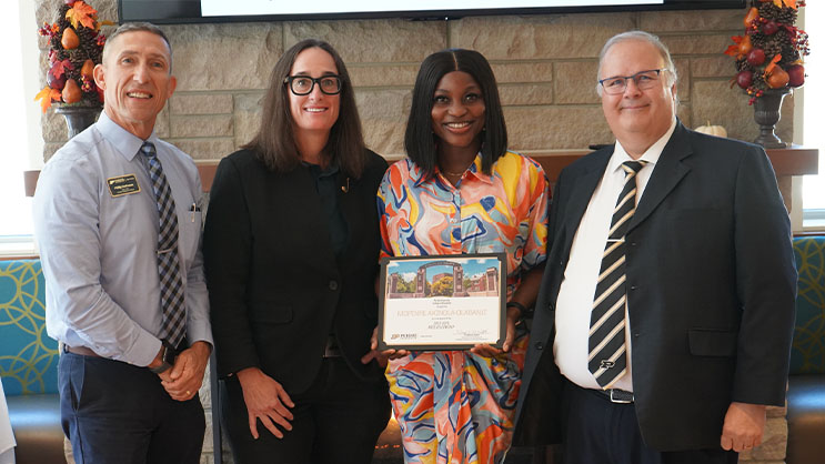 Mopinre Akinola-Olabanji holding a certificate. She is surrounded by Phil VanFossen, Katy Rusnak, and Wayne Wright.
