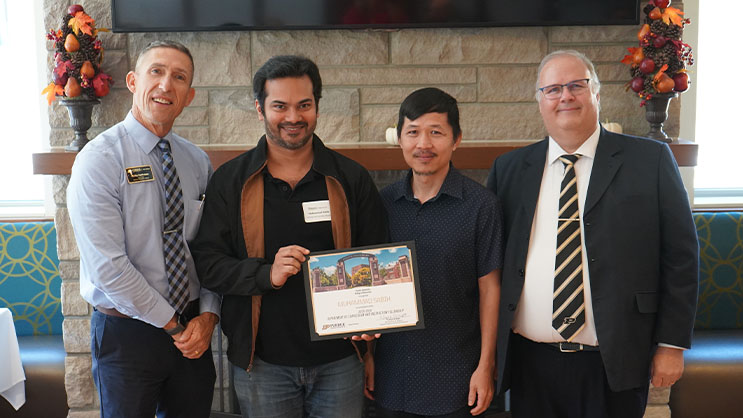Muhammad Sabih holding a certificate. He is surrounded by Phil VanFossen, Virak Chan, and Wayne Wright.