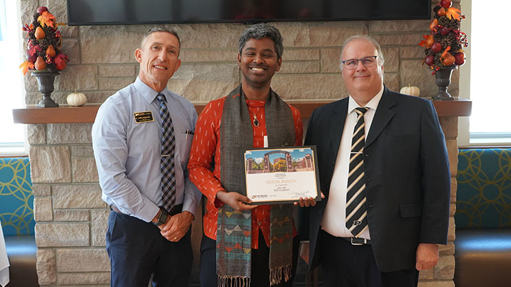 Nivedh Jayanth holding a certificate. He is surrounded by Phil VanFossen and Wayne Wright.