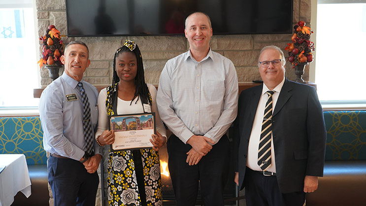 Nnenna Valentina Kalu holding a certificate. She is surrounded by Phil VanFossen, Eric Deemer, and Wayne Wright.