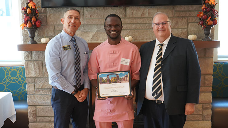 Obasanjo Fajemirokunholding a certificate. He is surrounded by Phil VanFossen and Wayne Wright.