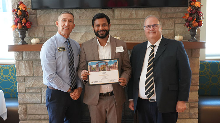 Pankaj Paul holding a certificate. He is surrounded by Phil VanFossen and Wayne Wright.