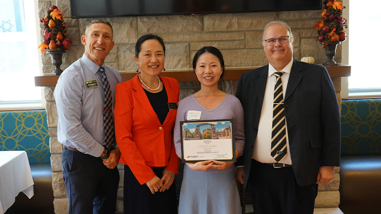 Yichen Wang holding a certificate. She is surrounded by Phil VanFossen, Yan Ping Xin, and Wayne Wright.