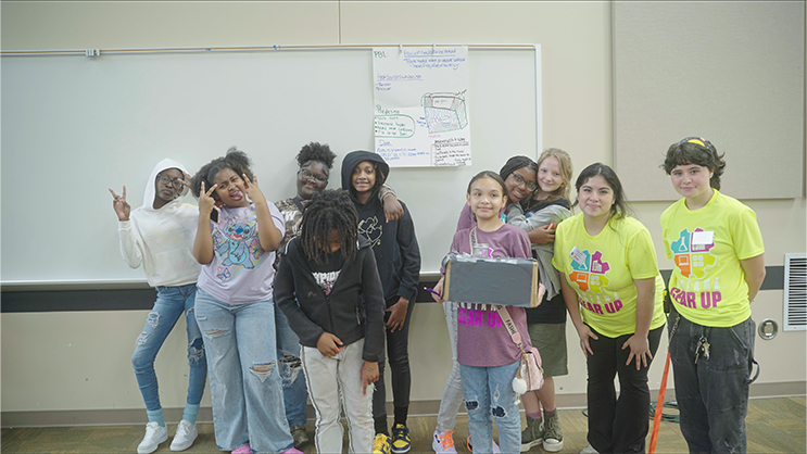 A group of GEAR UP students standing in front of a whiteboard and smiling.
