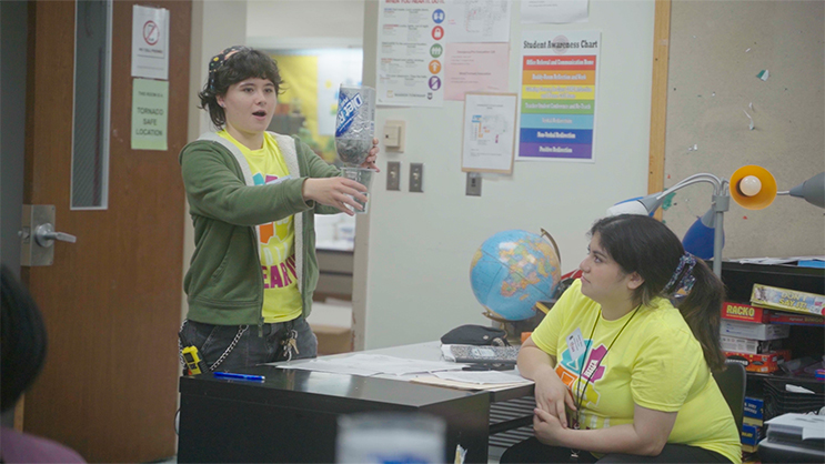A GEAR UP student holds a homemade water filter in front of him.