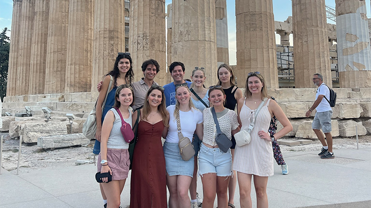 A group of ten Fulbright recipients standing in front of a large stone structure with pillars. 