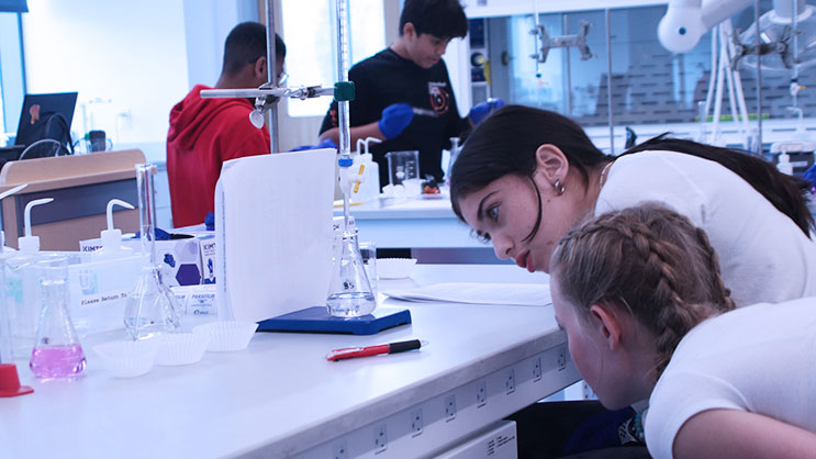 Two students examine a beaker in a science lab during GER2I's Summer Residential program.