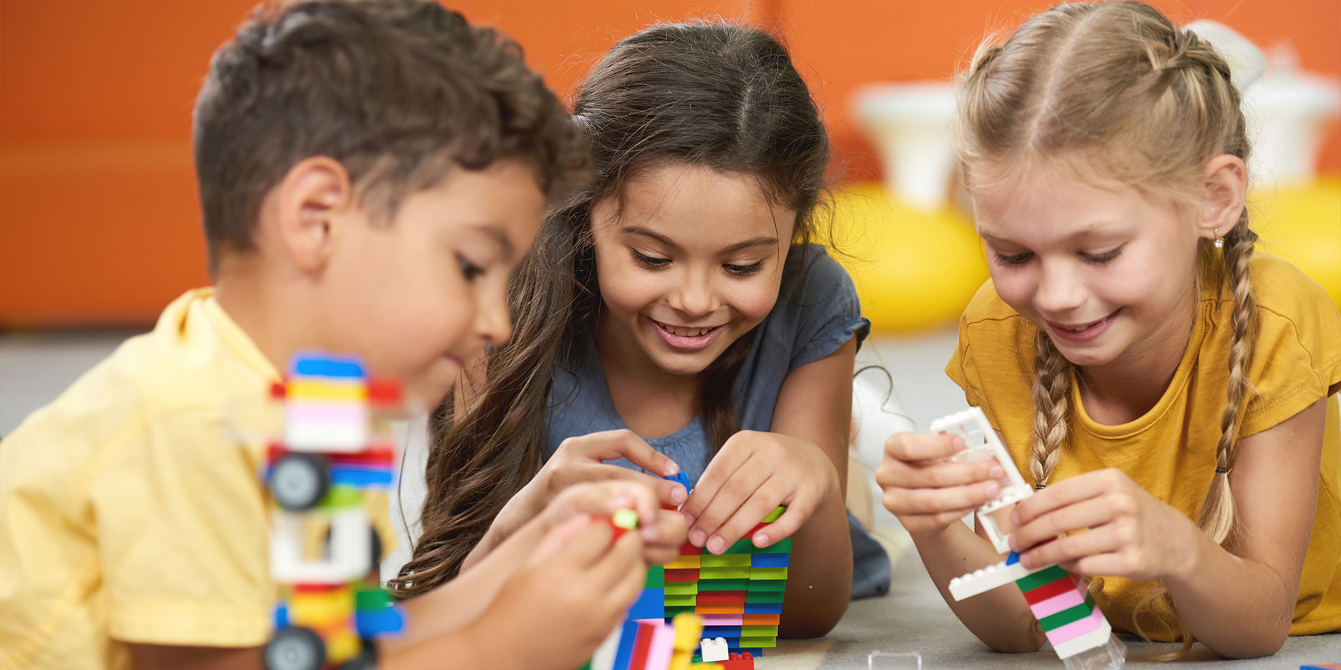 Three elementary school children playing with Lego.