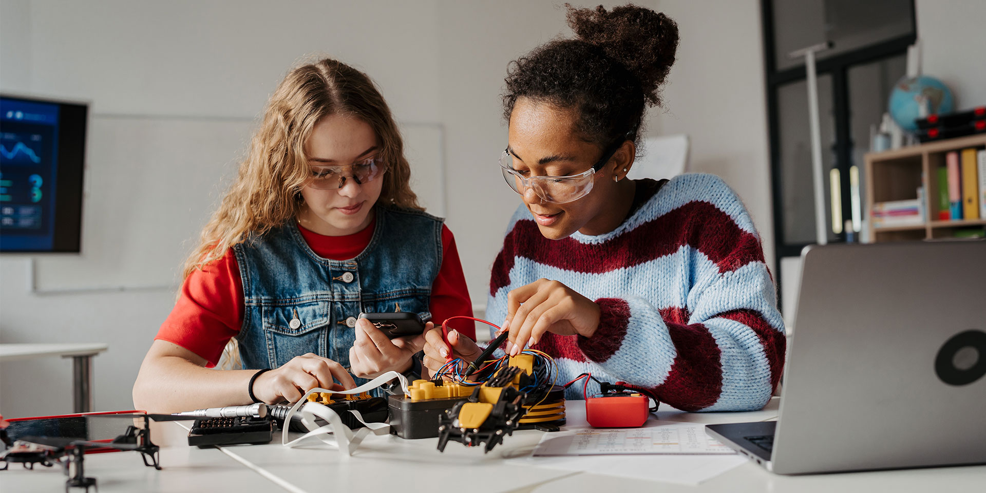 Two female students work on a robotics project.