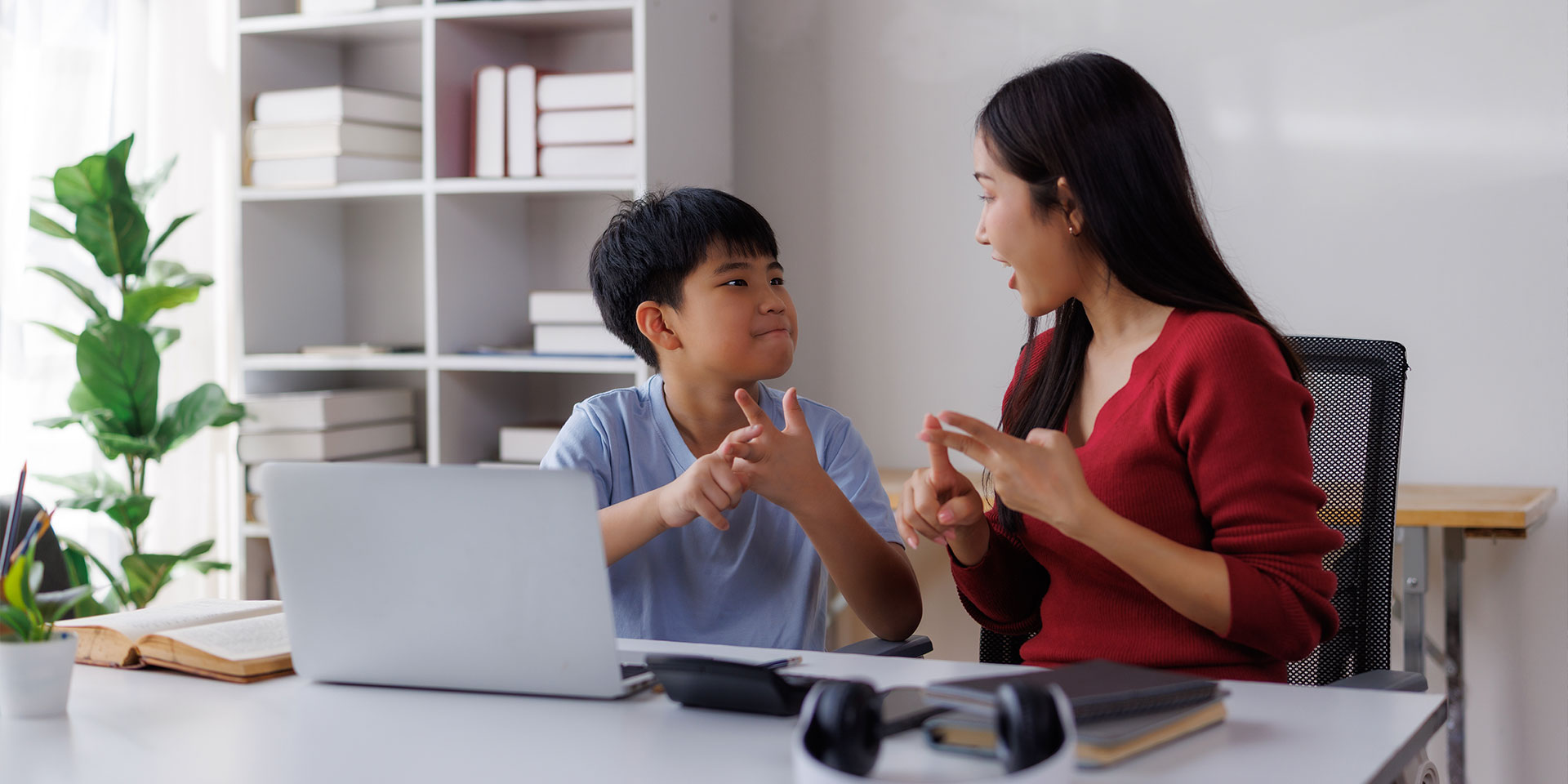 A teacher and student seated together and counting on their fingers.