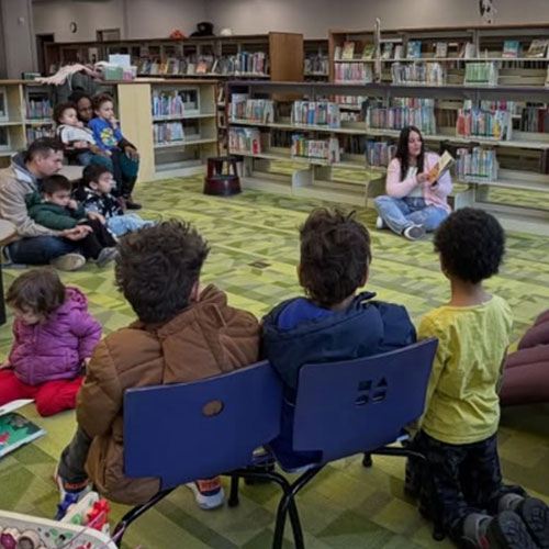 A volunteer reads to a large group of parents and their children during El Rincón Bilingüe at the library.