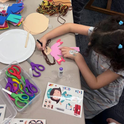 A child works on a paper doll craft after El Rincón Bilingüe storytime at the library.