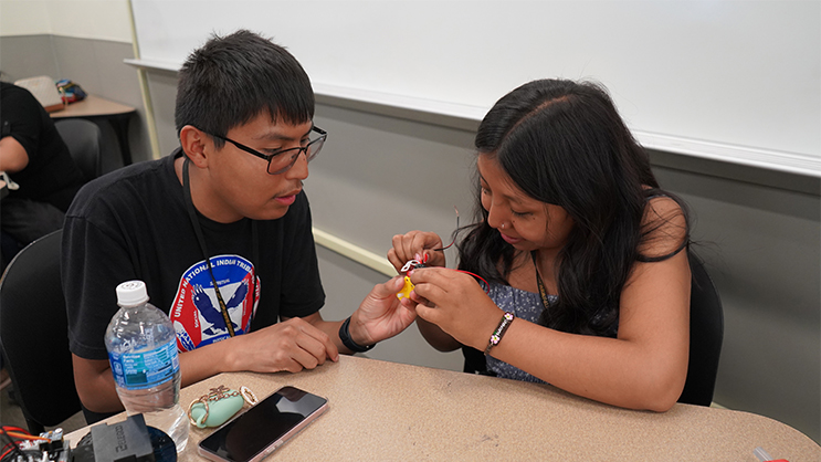 Two students working together on the wiring of a miniature car.