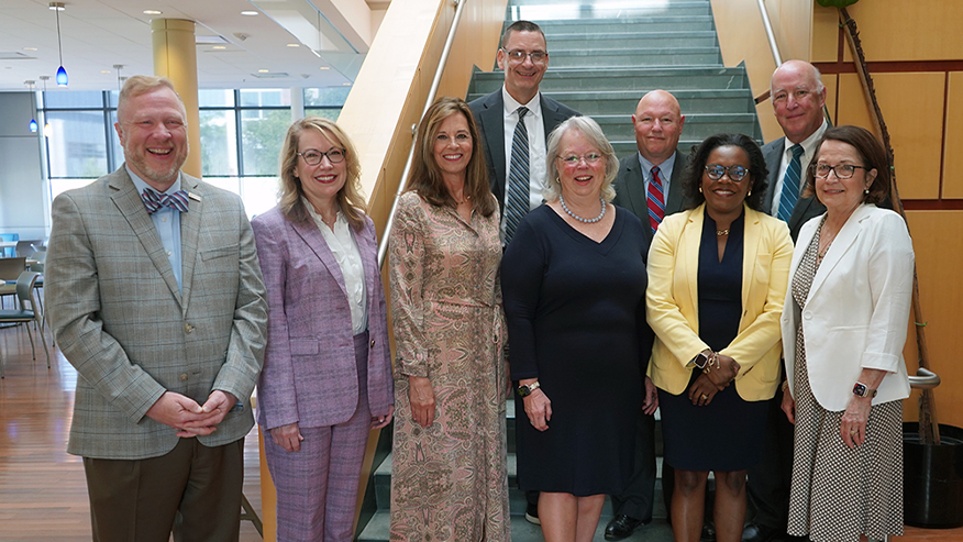 An indoor group photo of nine Indiana lawyers and justices standing in front of a staircase.