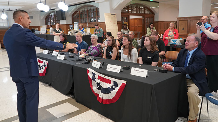 Phil VanFossen standing in front of a group of seated student Quiz Off competitors.
