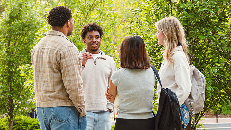 A group of students talk outside on Purdue University's campus