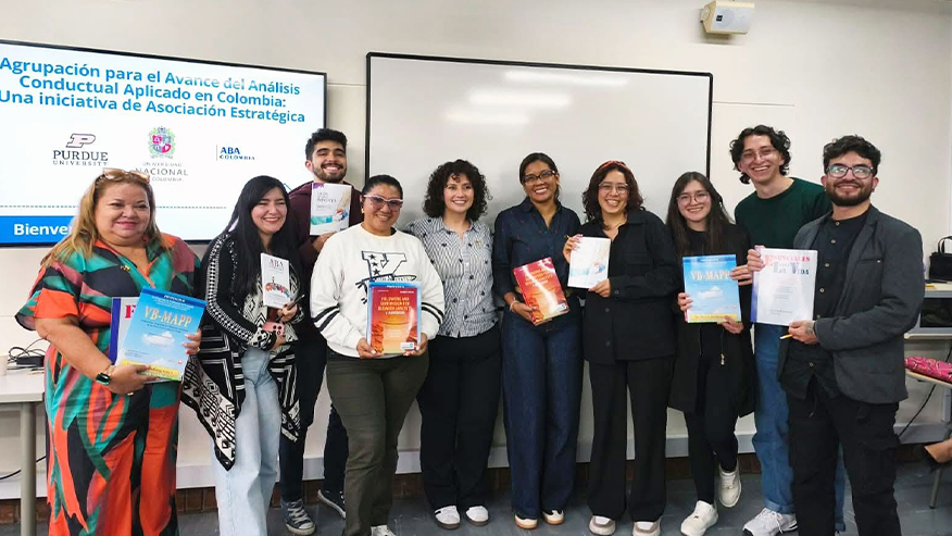 Juliana Aguilar with a group of students from the Nacional Universidad de Colombia. They are each holding up a book and smiling.