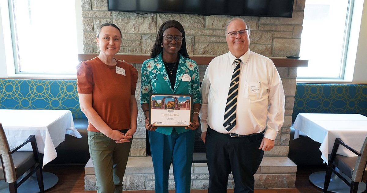 Bukola Abiiba holding a certificate. She is surrounded by Jasmine Begeske and Wayne Wright.
