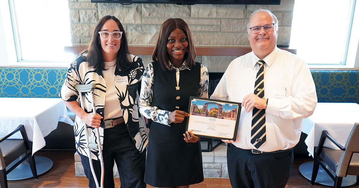 Mopinre Akinola-Olabanji holding a certificate. She is surrounded by Katy Rusnak and Wayne Wright.